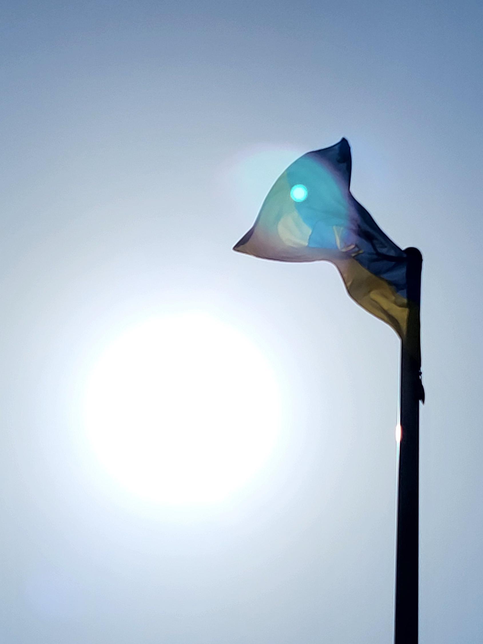Wehende Flagge von Castrop-Rauxel vor blauem Himmel und strahlender Sonne