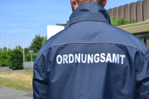 Mensch mit Jacke und Aufdruck Ordnungsamt von hinten