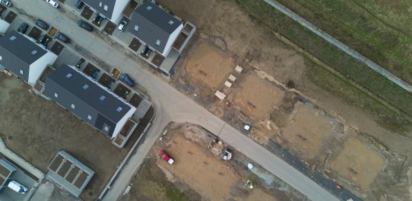 Vogelansicht auf ein Neubaugebiet mit H&auml;usern und leeren Grundst&uuml;cken