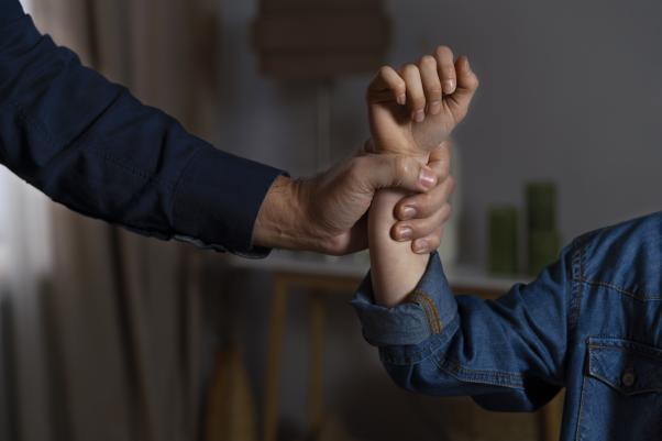 Mensch greift andere Person gewaltvoll am Arm.