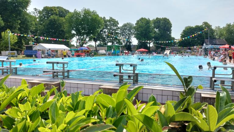 Das Bild zeigt das gro&szlig;e Schwimmbecken im Parkbad Nord w&auml;hrend des Freibadfestes mit Personen im Becken und am Rand.