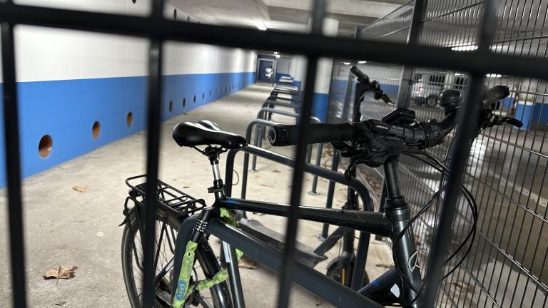 Ein Fahrrad und ein E-Roller hinter einem Zaun an einer Abstellanlage