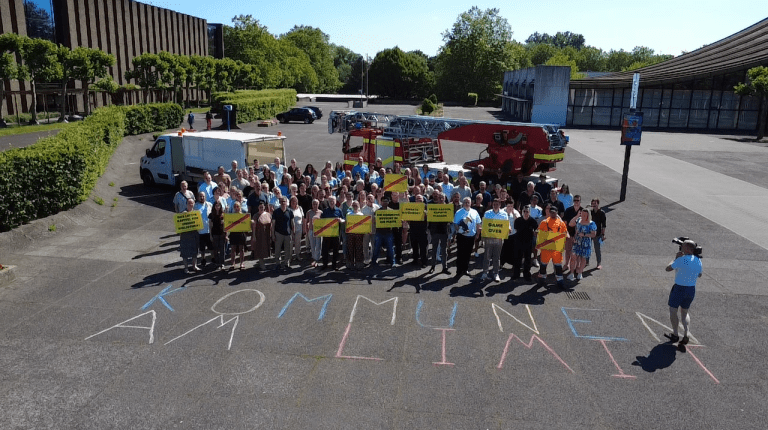 Luftbild von Menschen mit gelben Plakaten und Feuerwehrfahrzeug im Hintergrund.