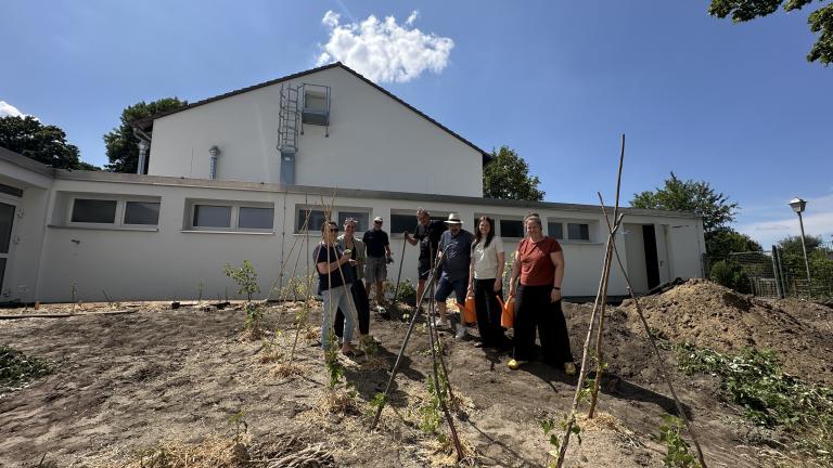 Personen stehen im neuen Gemeinschaftsgarten in Merklinde